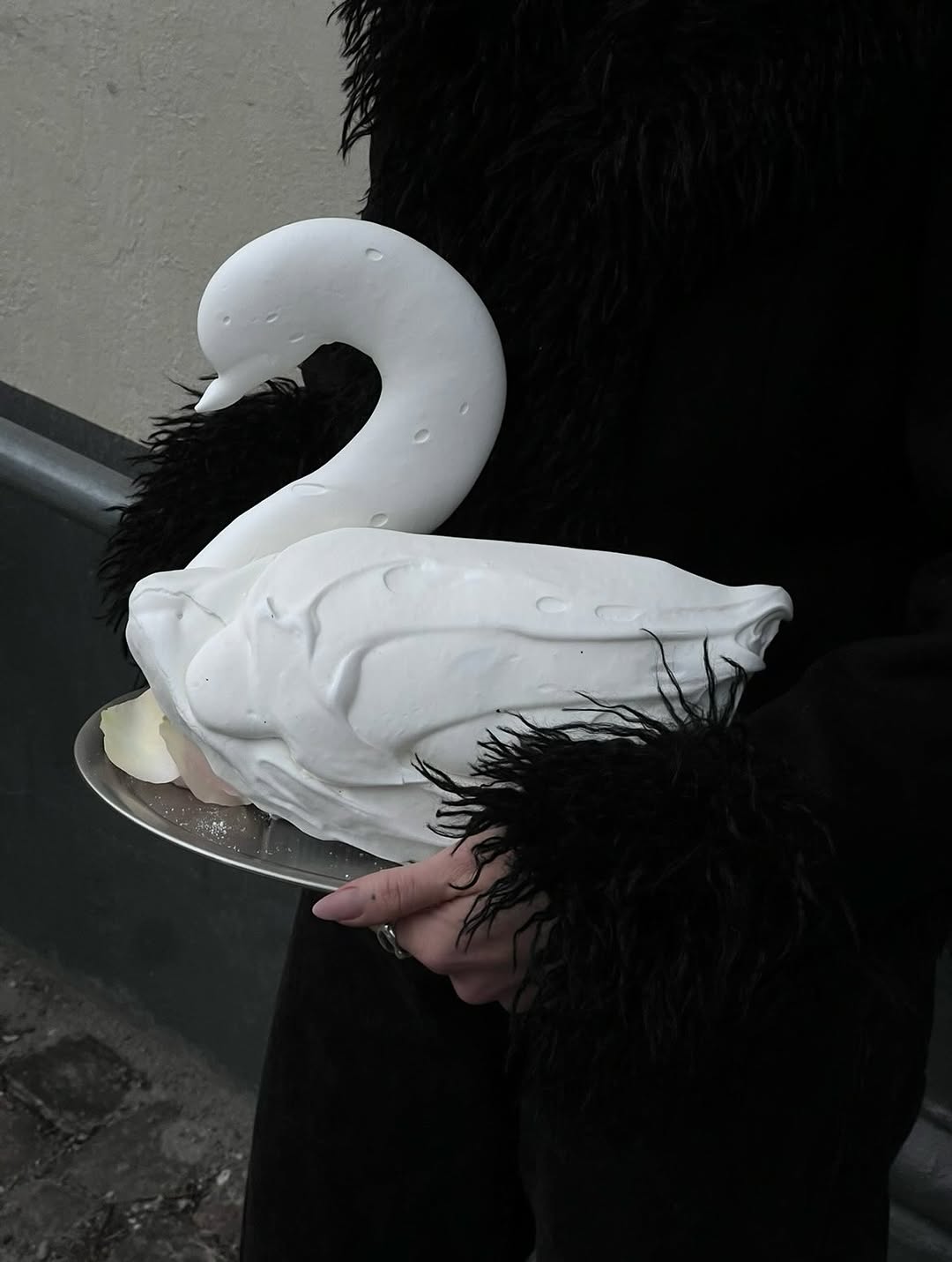 Swan-shaped pastry sculpture, hand-held outdoors